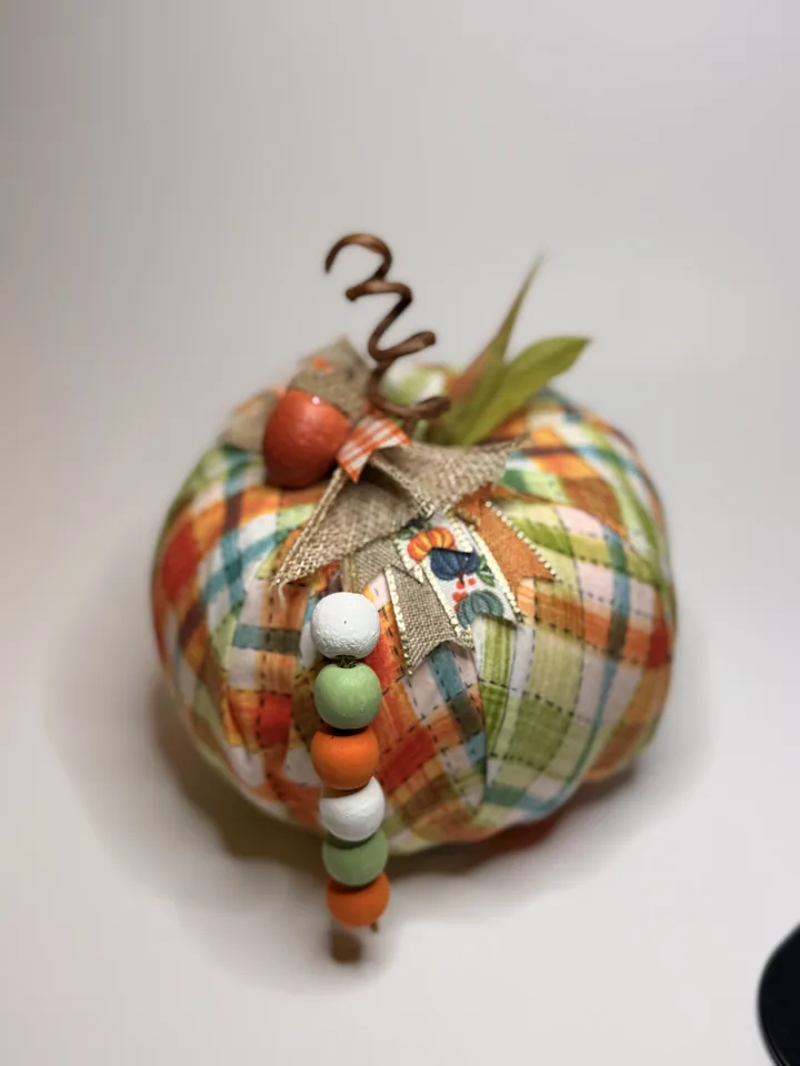 Colorful patchwork fabric pumpkin with a curled wire stem, acorn accents, burlap ribbon, and orange, sage, and cream wood beads.